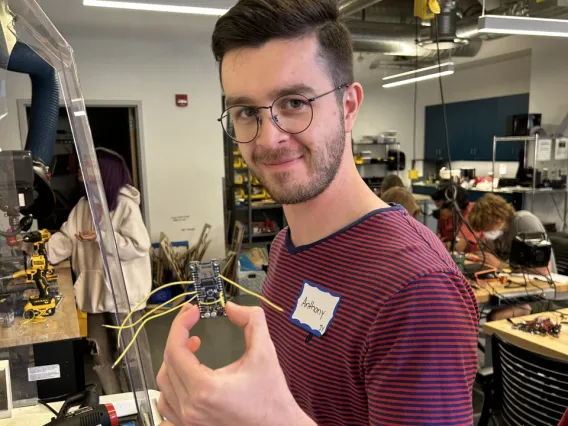 A male student holding up an electronic device