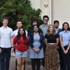 The ten student participants are seen standing outdoors in two rows in front of the white base of the telescope dome in back of Steward Observatory